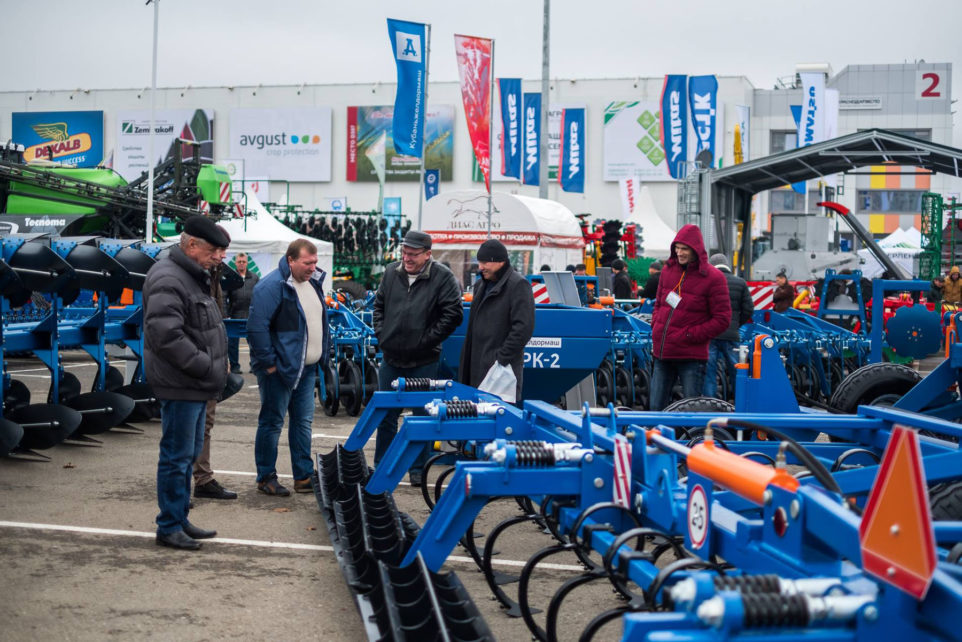 Modern factory facility with industrial equipment and workers in blue coveralls, bright industrial lighting, professional manufacturing environment